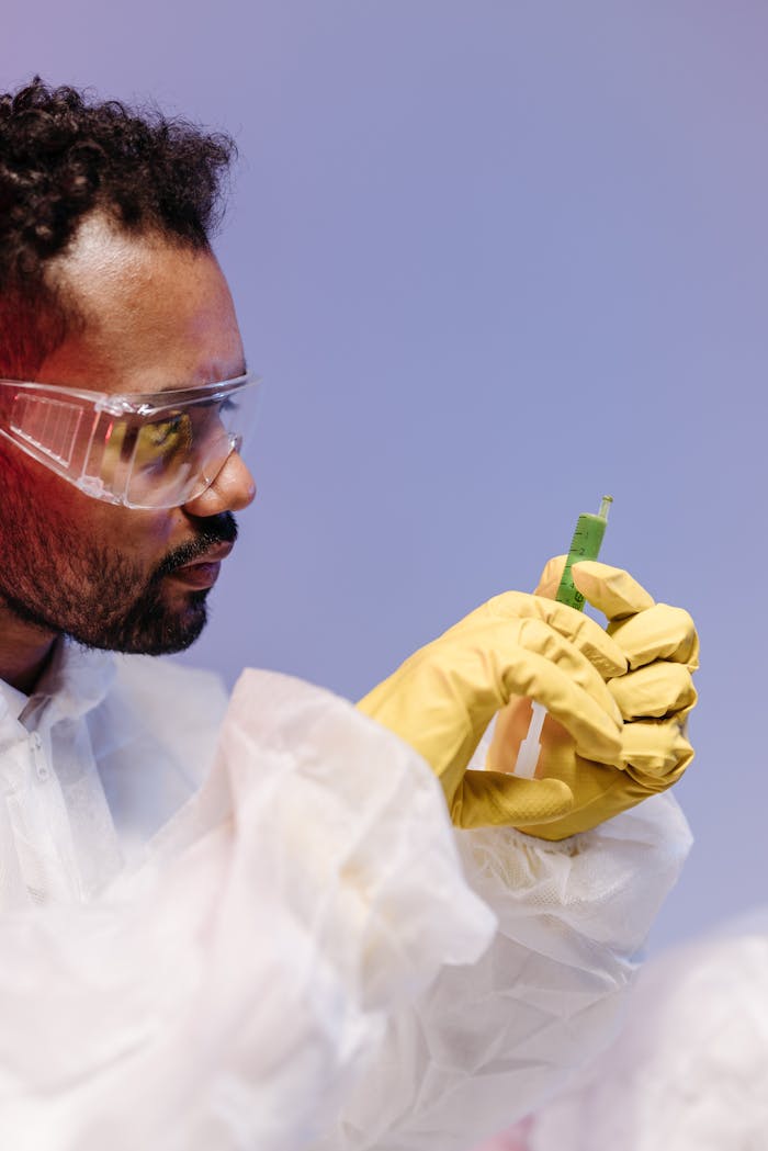 Scientist wearing protective gear analyzing a sample in a laboratory setting.