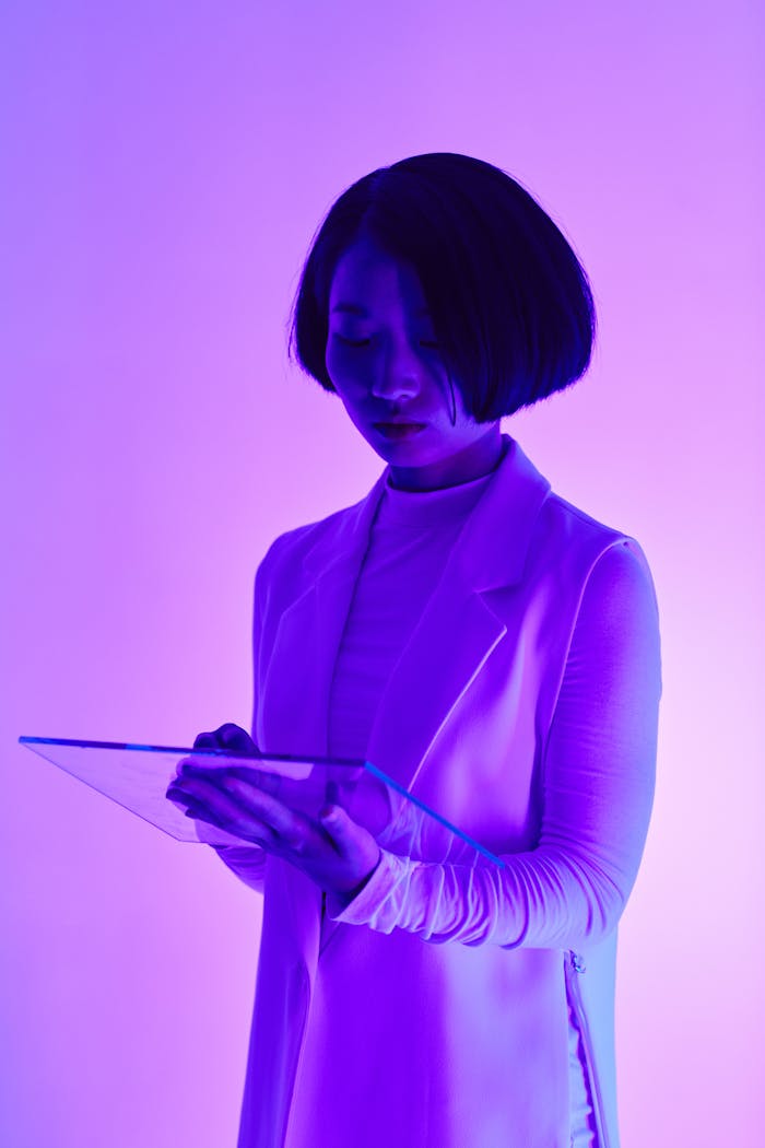 A woman interacts with a transparent digital tablet in a futuristic, neon-lit environment.